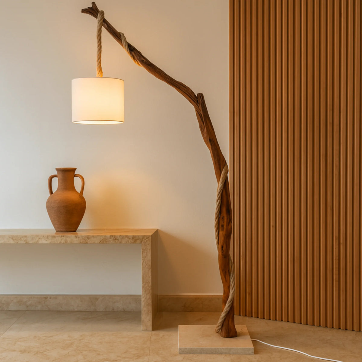 Lampadaire d'entrée en bois naturel au-dessus d'une console claire et d'une jarre en terre cuite