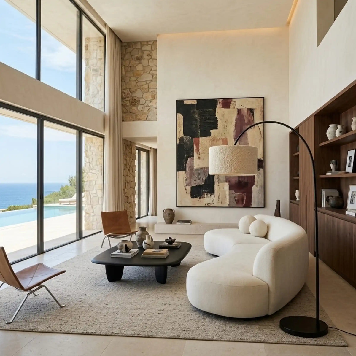Lampadaire girafe près d'un canapé courbe blanc dans un salon à double hauteur avec vue sur la mer