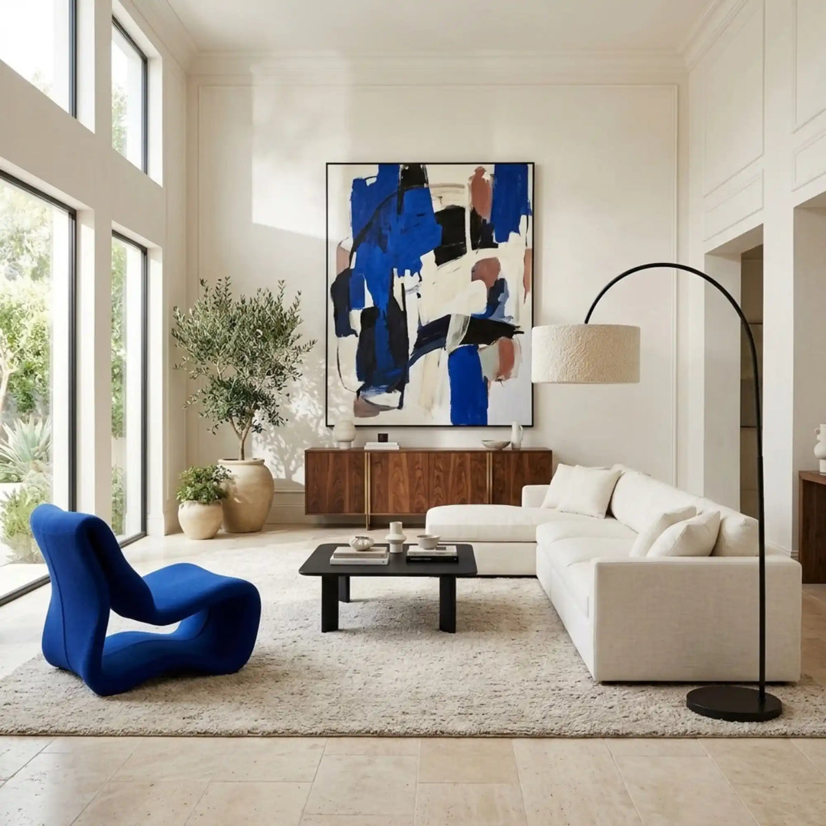 Lampadaire girafe au-dessus d'un canapé d'angle blanc, avec fauteuil bleu électrique et tableau bleu dans un salon lumineux