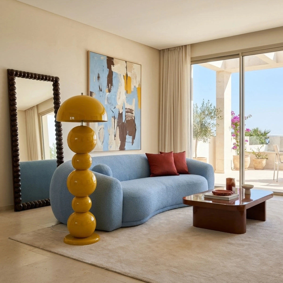 Lampadaire jaune à boules à côté d'un canapé bleu arrondi, devant un miroir et une baie vitrée