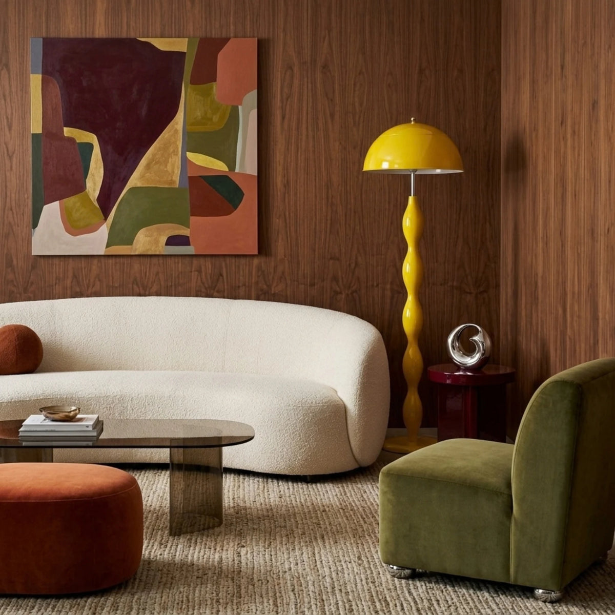 Lampadaire jaune à abat-jour en dôme dans un salon boisé, avec canapé courbe écru, fauteuil olive et tableau abstrait.