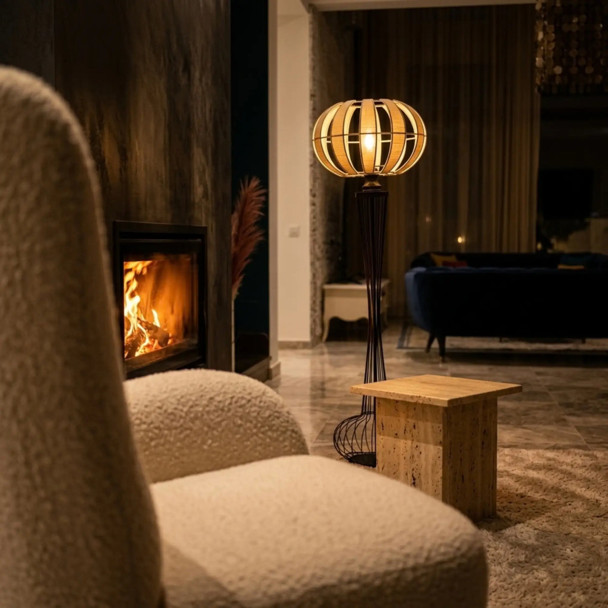 Lampadaire allumé diffusant une lumière chaude près d'une cheminée en soirée, à côté d'un fauteuil bouclette