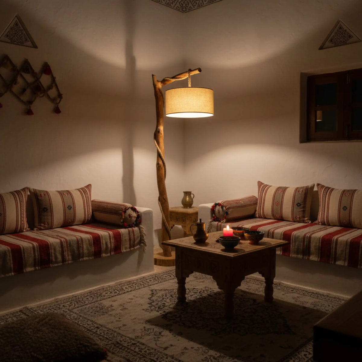 Lampadaire en bois flotté diffusant une lumière chaude dans un salon traditionnel à banquettes rayées rouges