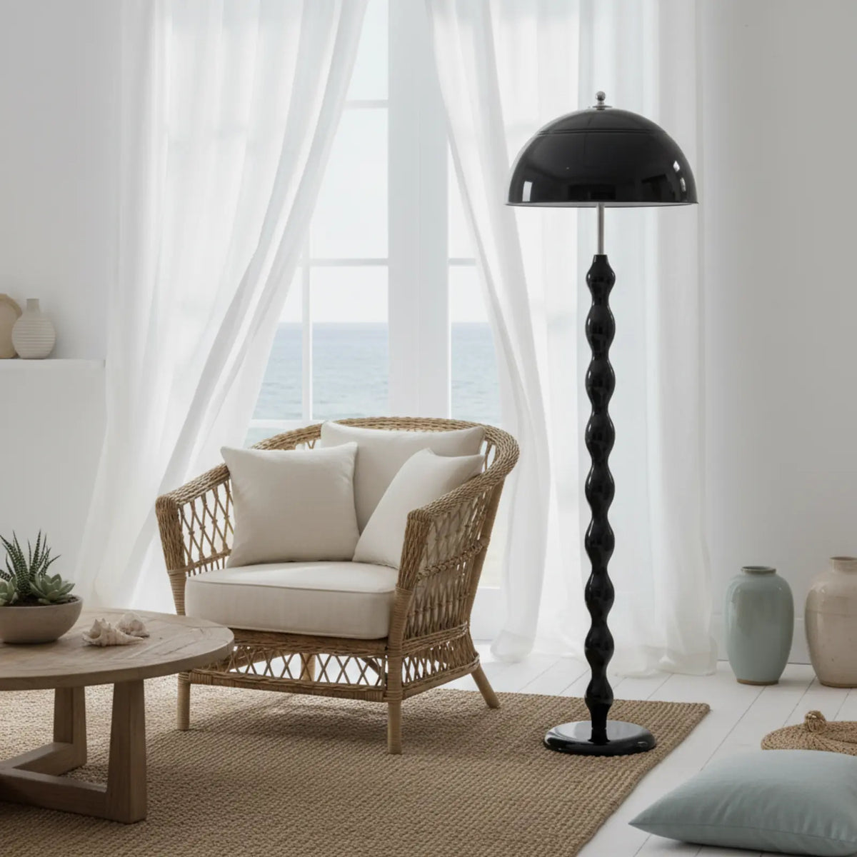 Lampadaire noir à côté d'un fauteuil en osier, devant des voilages blancs avec vue sur la mer