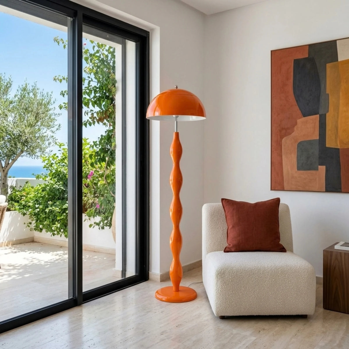 Lampadaire orange à pied ondulé près d'un fauteuil écru et d'une baie vitrée ouverte sur des oliviers