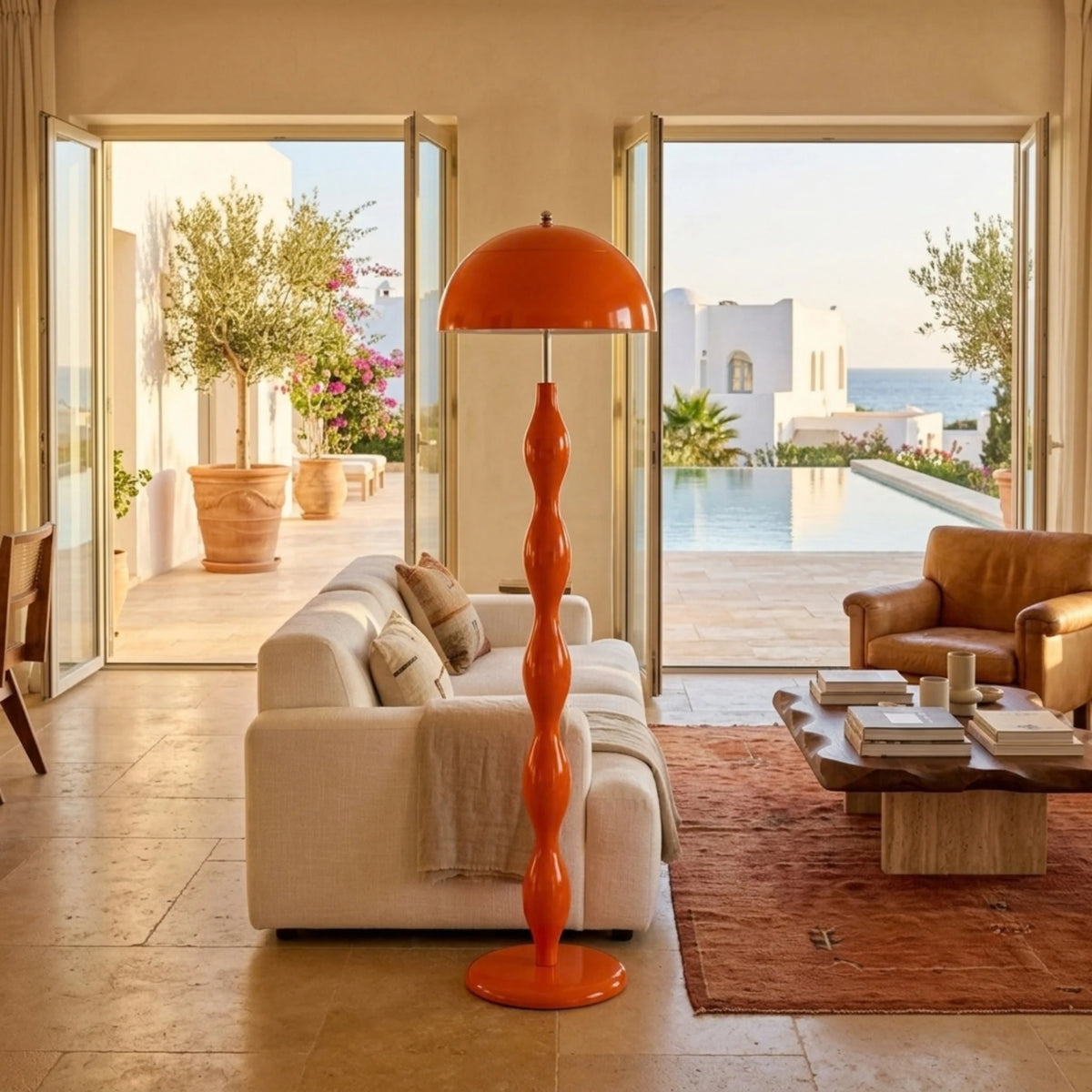 Lampadaire orange fait main dans un salon ouvert sur une terrasse avec piscine, tapis berbère et canapé crème