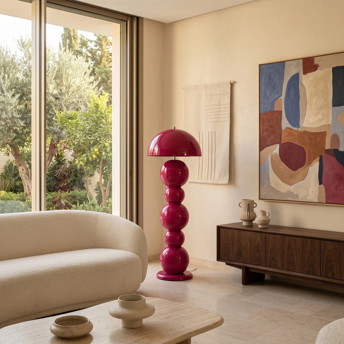 Lampadaire pop rose fuchsia près d'un canapé arrondi écru et d'un buffet en noyer, vue sur le jardin