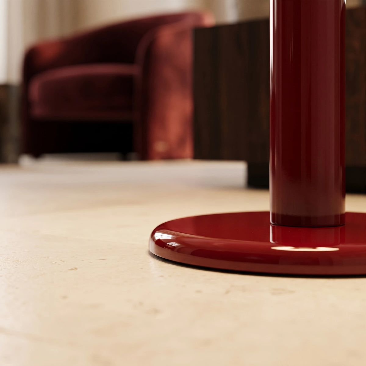 Détail du socle rond rouge carmin du lampadaire posé sur un sol en pierre claire