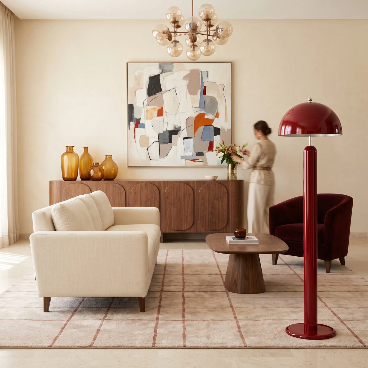 Lampadaire design rouge carmin à côté d'un canapé crème et d'un buffet en noyer avec vases ambrés