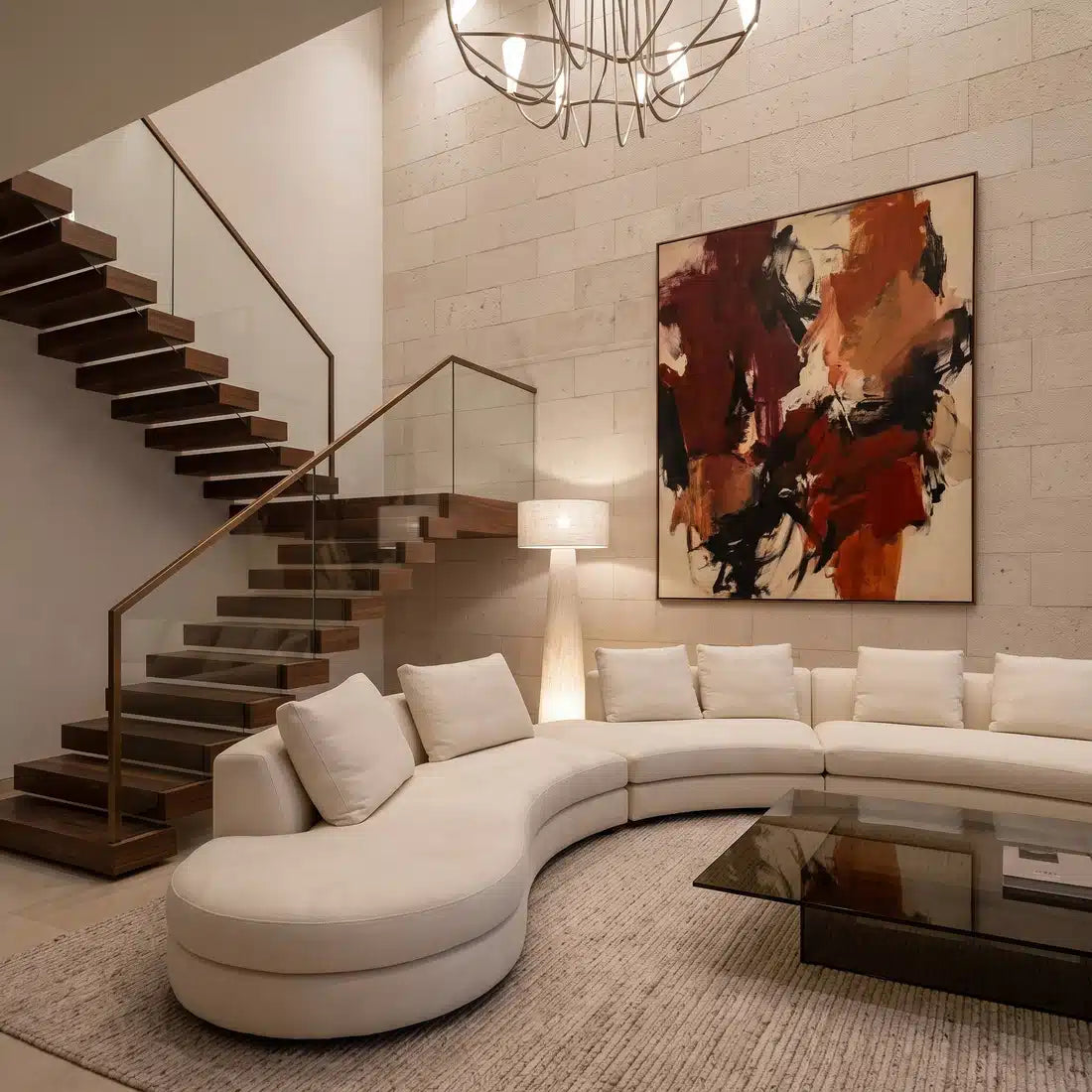 Lampadaire lin allumé près d'un escalier suspendu, derrière un grand canapé courbe blanc