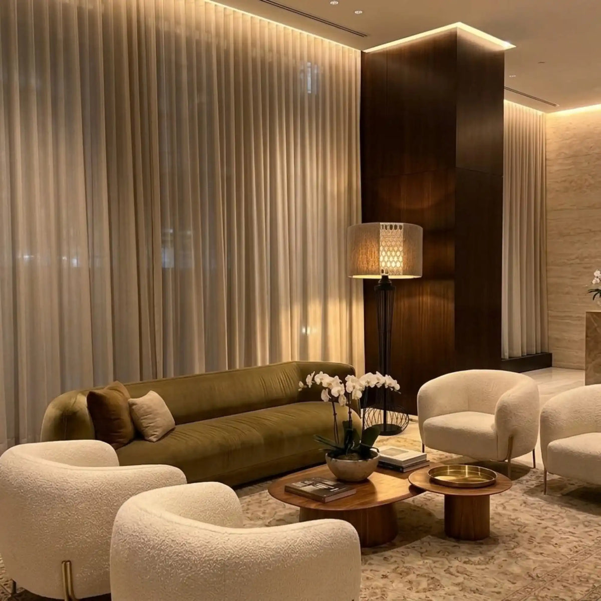 Lampadaire en jute dans un salon chic avec canapé en velours olive, fauteuils bouclette et orchidée blanche