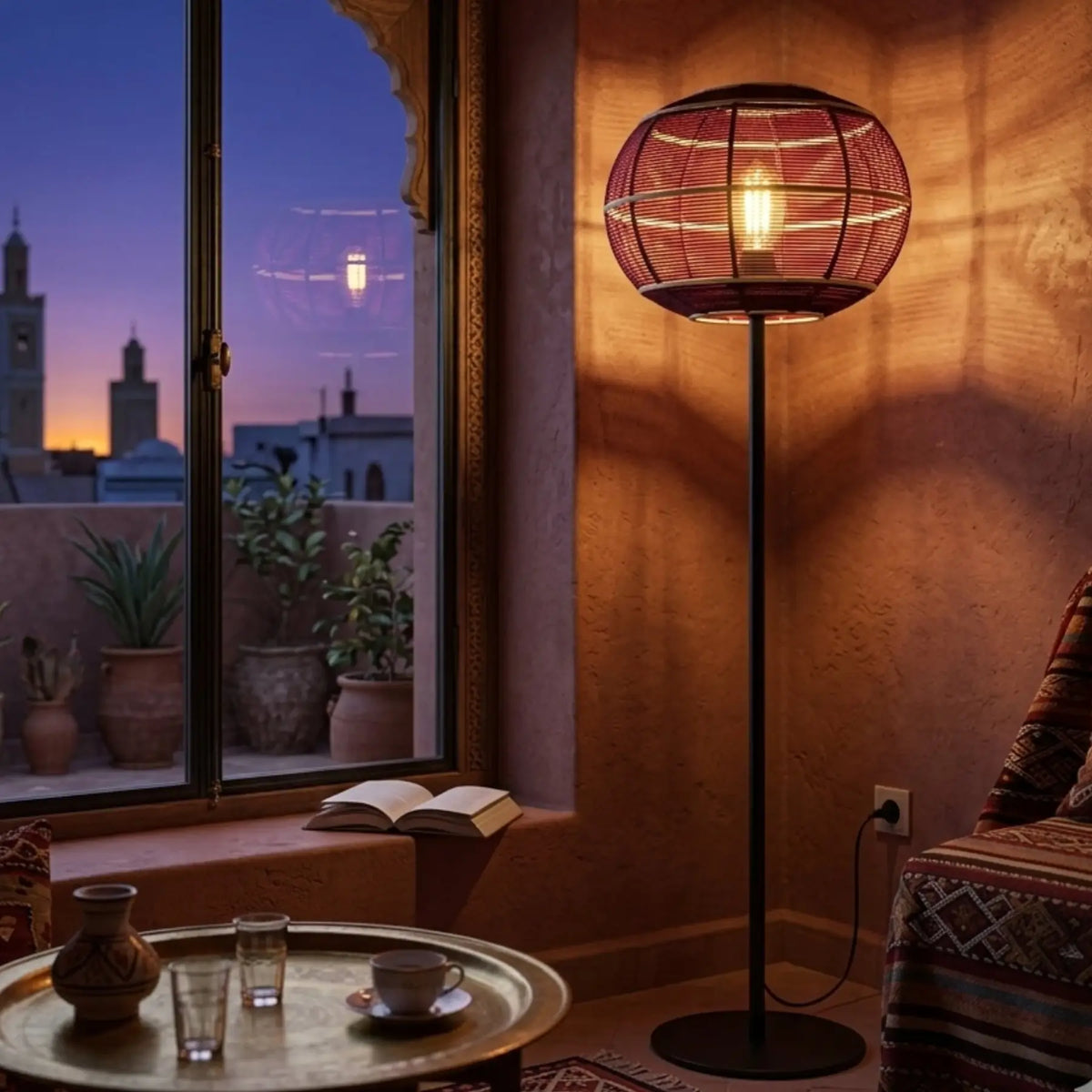 Lampadaire en fil de coton bordeaux allumé le soir dans un salon oriental avec plateau en cuivre