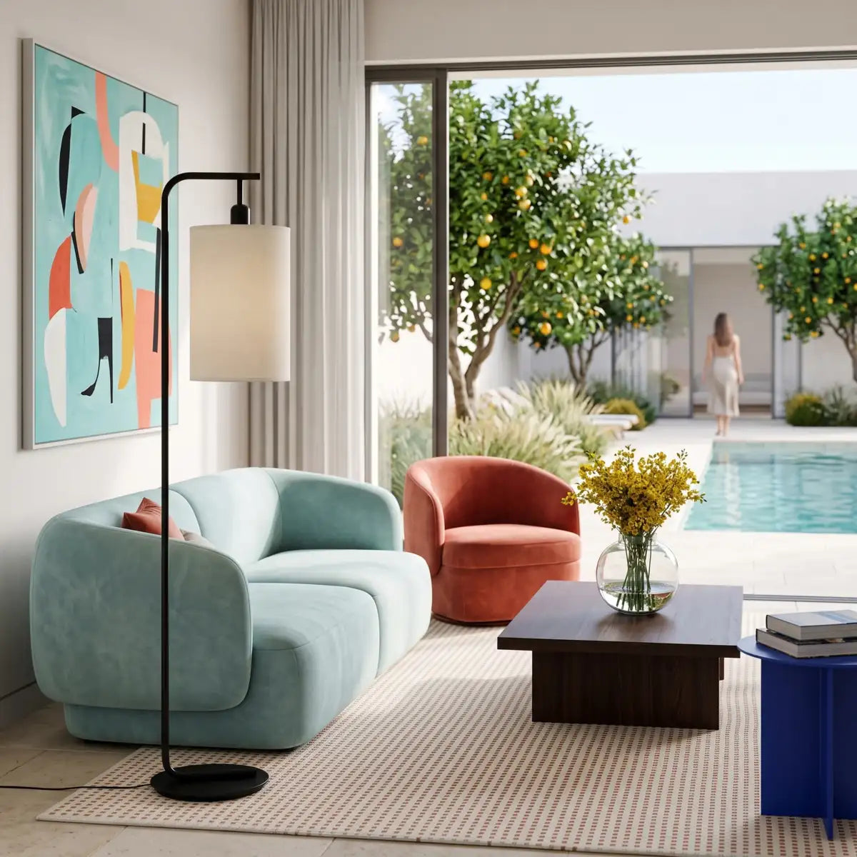 Lampadaire noir près d'un canapé bleu clair, dans un salon ouvert sur une piscine et des orangers