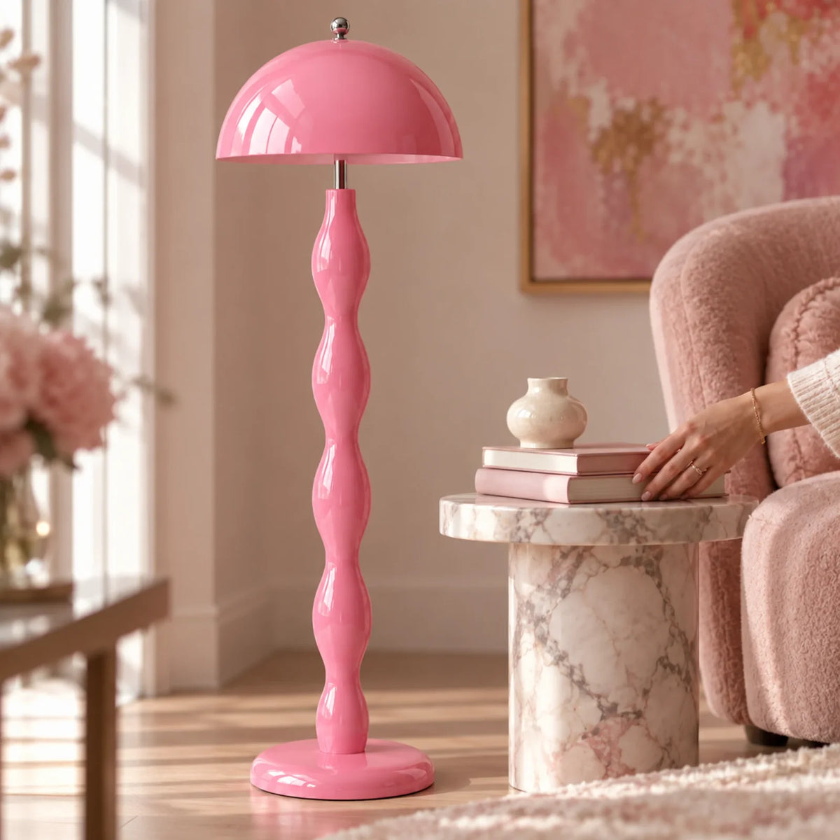 Lampadaire rose pastel dans un salon, près d'un fauteuil rose bouclé et d'une table d'appoint en marbre