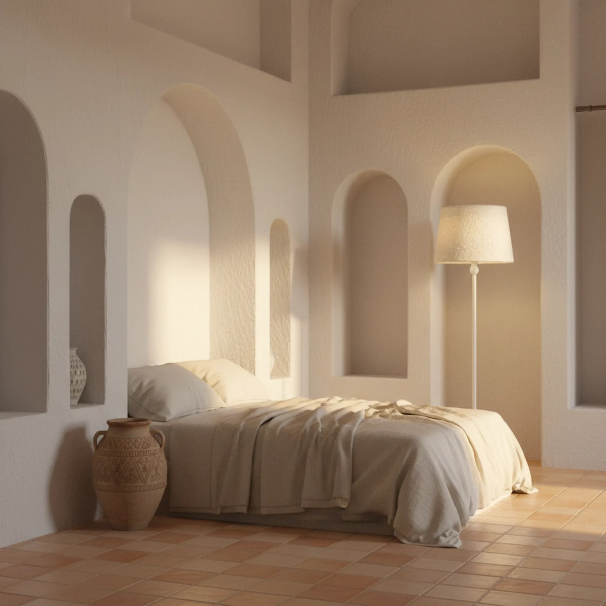 Lampadaire blanc dans une chambre aux murs blancs à niches en arche, sol en tomettes et jarre en terre cuite