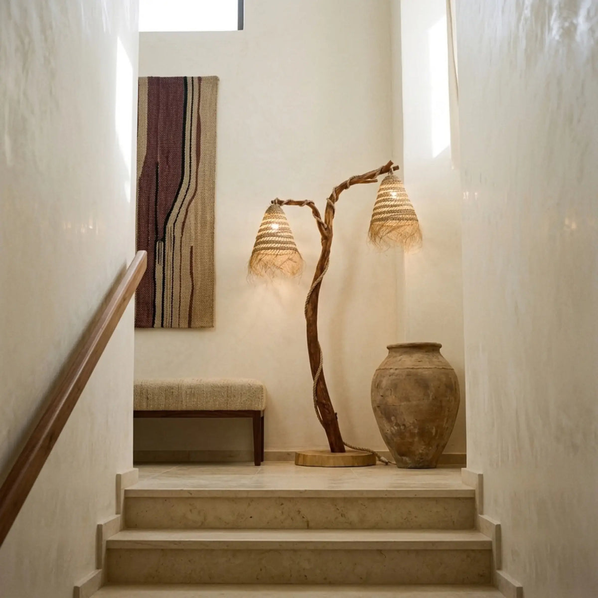Lampe sur pied en bois flotté sur un palier d'escalier, près d'une jarre en terre cuite et d'un banc