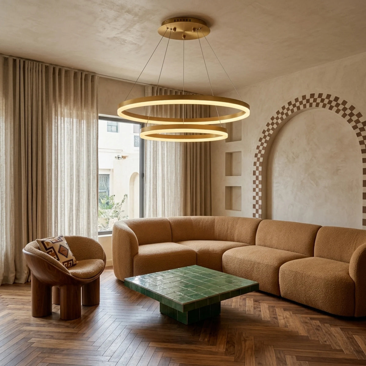 Lustre à anneaux LED doré dans un salon avec canapé terracotta et arche à damier