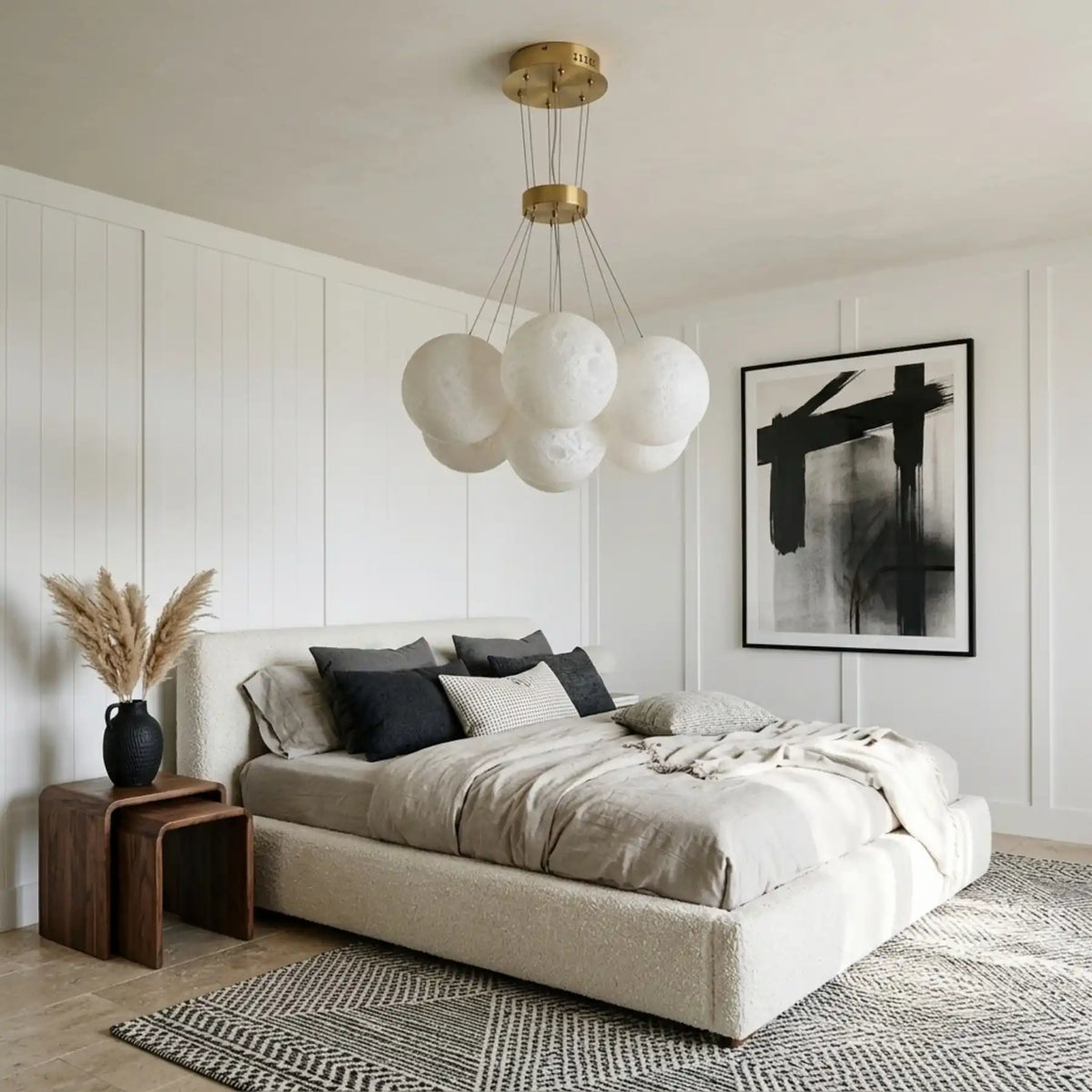 Lustre boules blanches suspendu au-dessus d'un lit beige dans une chambre épurée aux murs blancs