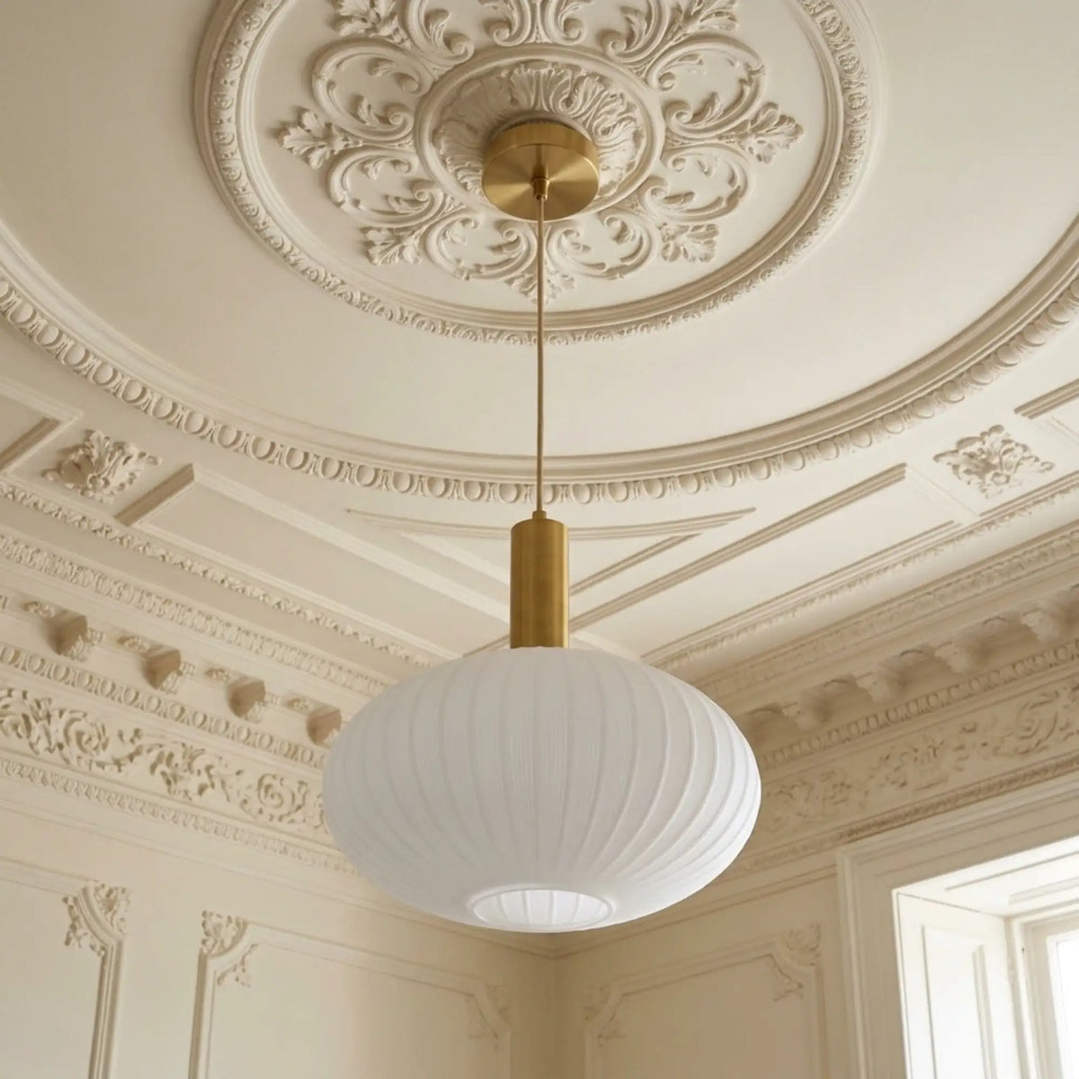 Lustre ovale en verre opale cannelé suspendu sous une rosace de plafond ornée de moulures