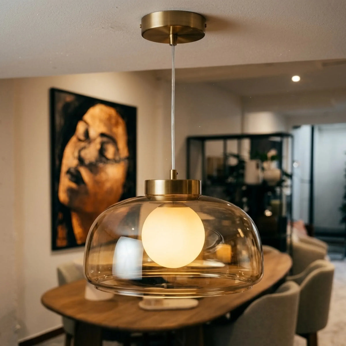 Lustre en verre fumé doré allumé, globe opale lumineux, au-dessus d'une table de salle à manger en bois