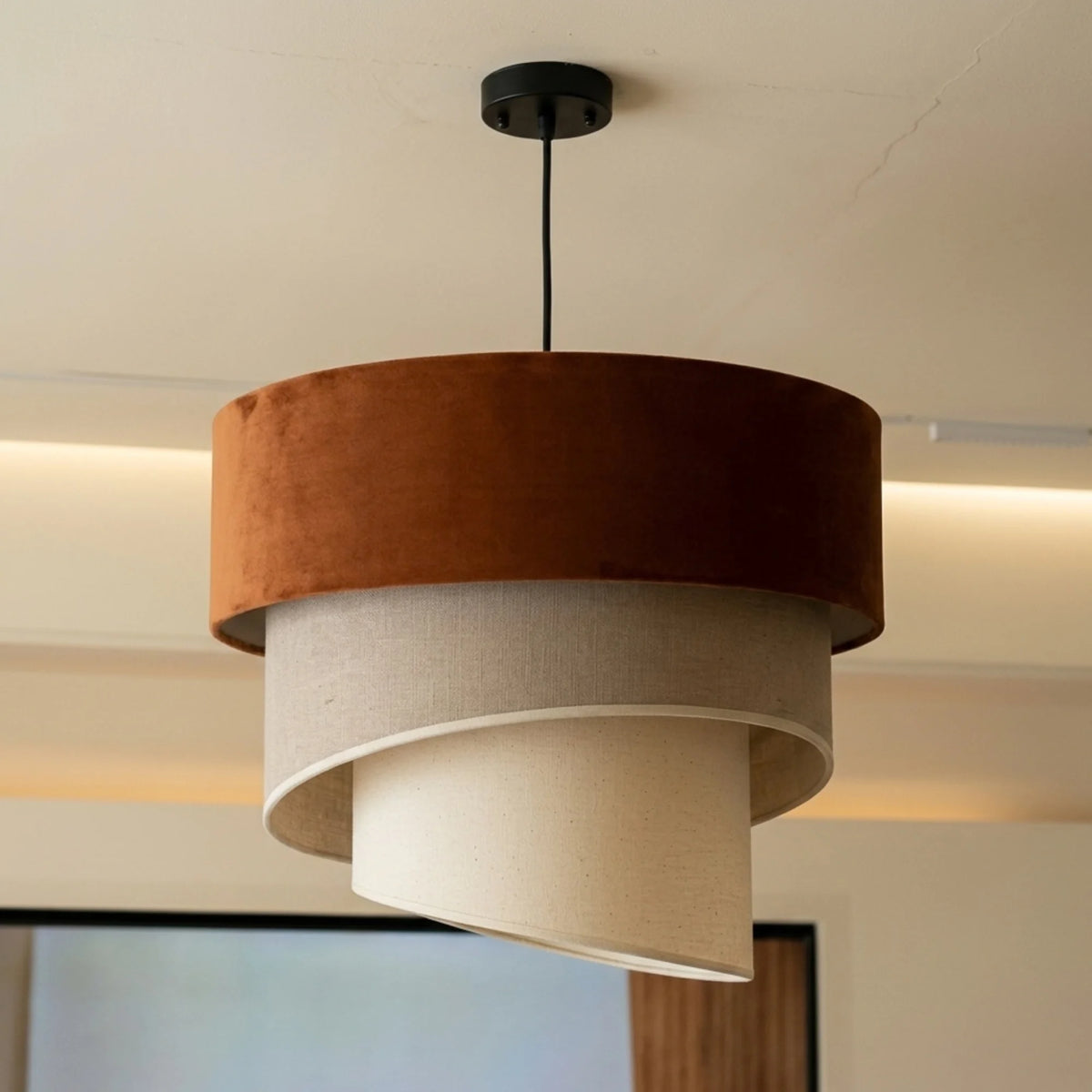 Gros plan sur le tambour en velours terracotta et les spirales beige crème du lustre