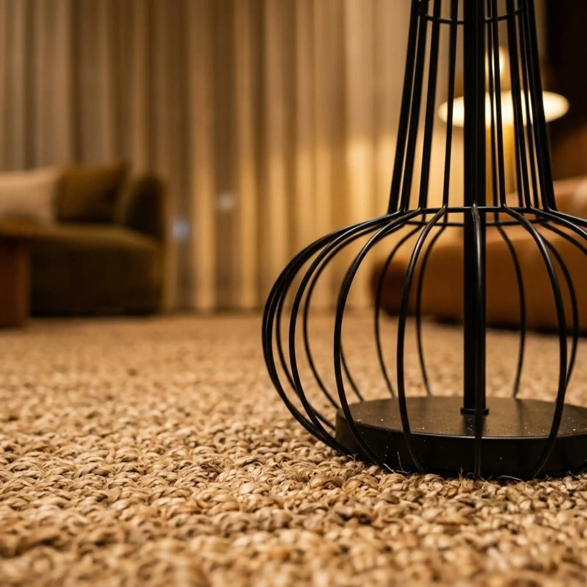 Détail du pied en cage de fil métallique noir du lampadaire, posé sur un tapis bouclé