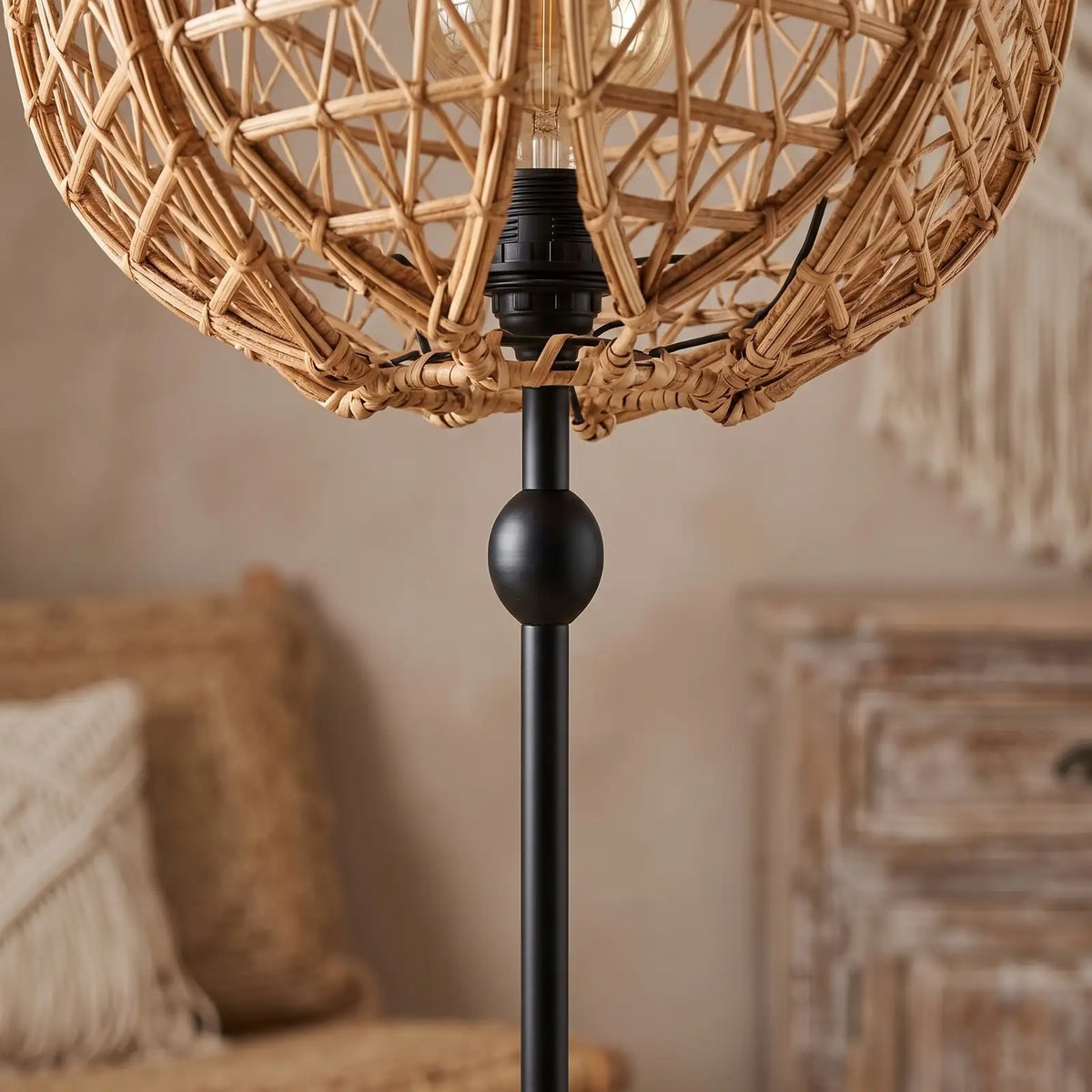 Détail du pied en métal noir et de la douille sous l'abat-jour en fibre de palmier du lampadaire