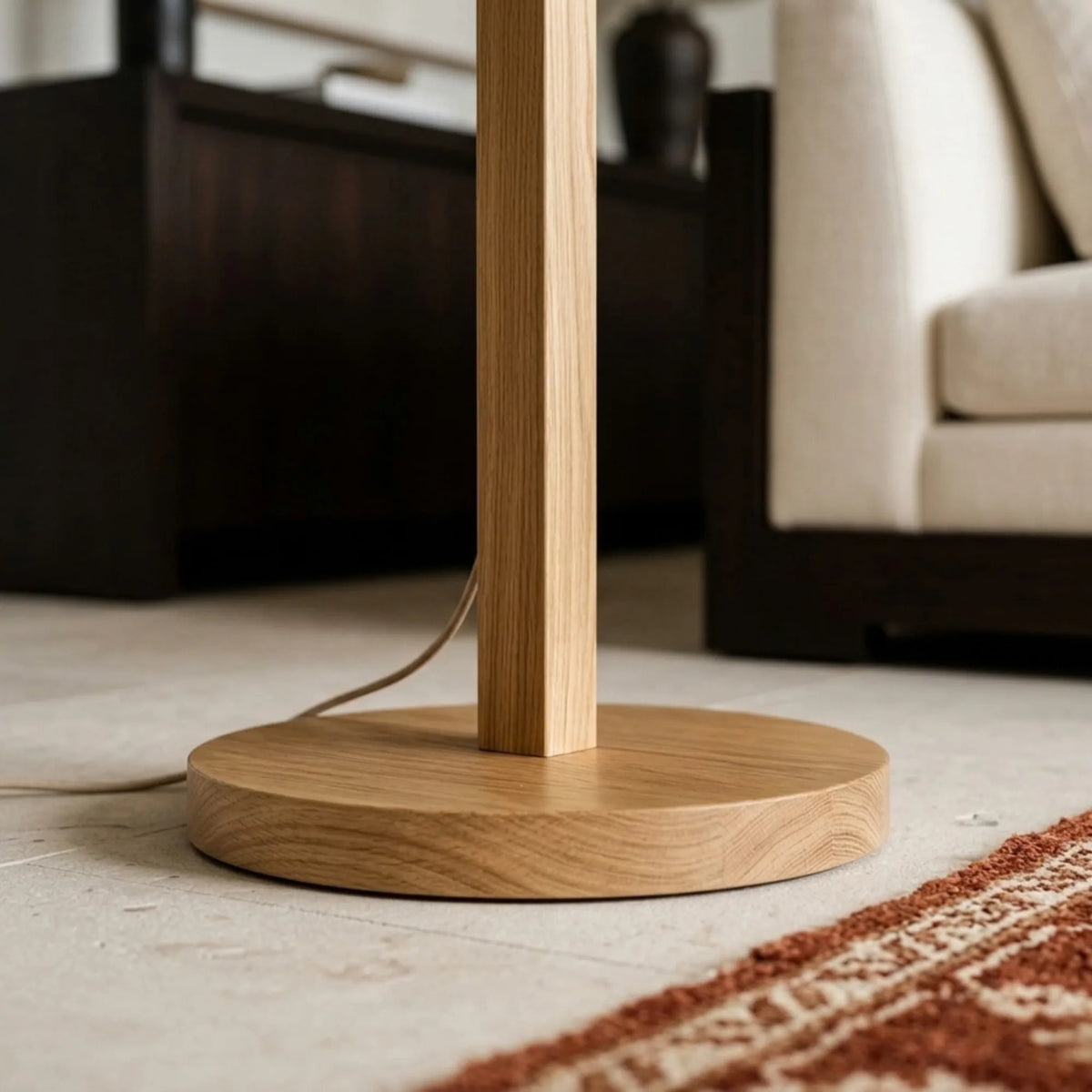 Gros plan du socle rond et du pied carré en bois naturel du lampadaire, posé dans un salon