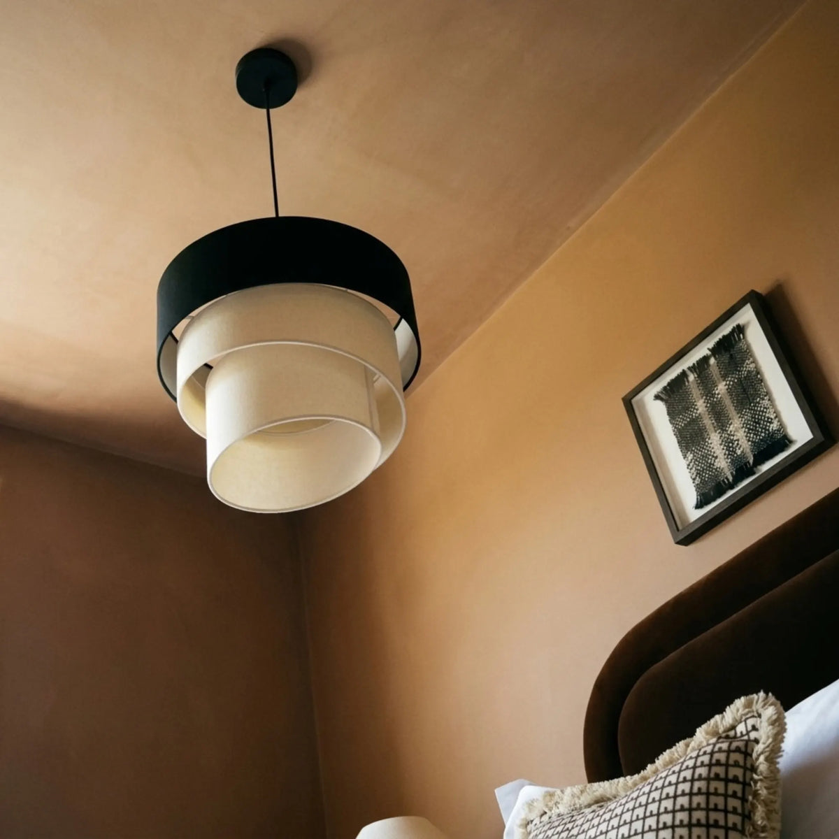 Vue en contre-plongée de la spirale de tissu écru sous le tambour noir, plafond terracotta