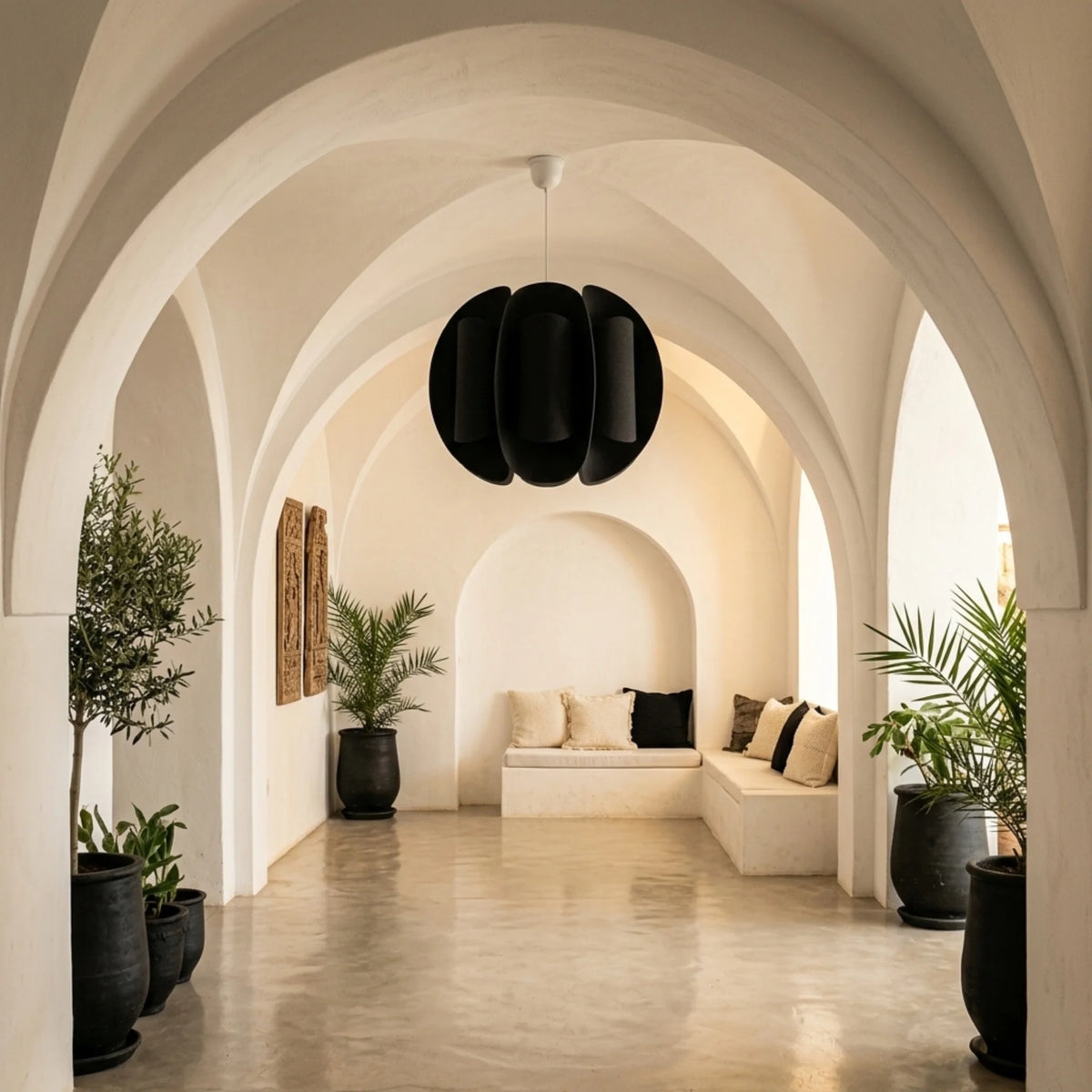 Suspension boule noire dans un couloir blanc voûté à arches avec plantes et banquette
