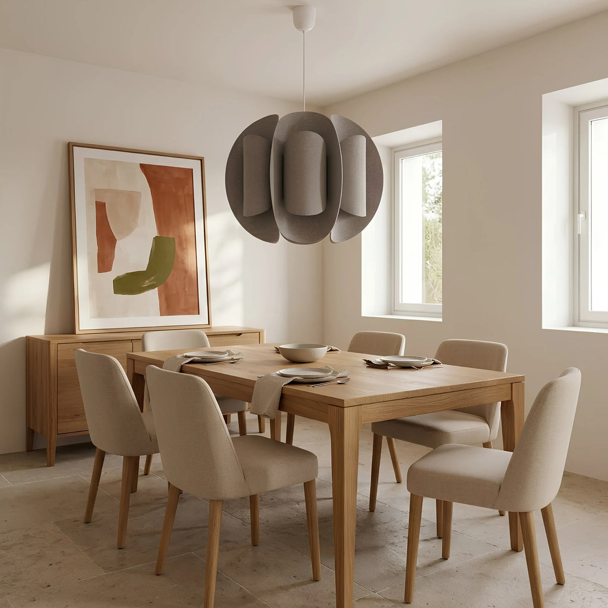 Suspension taupe au-dessus d’une table en bois clair et de chaises beiges dans une salle à manger lumineuse.