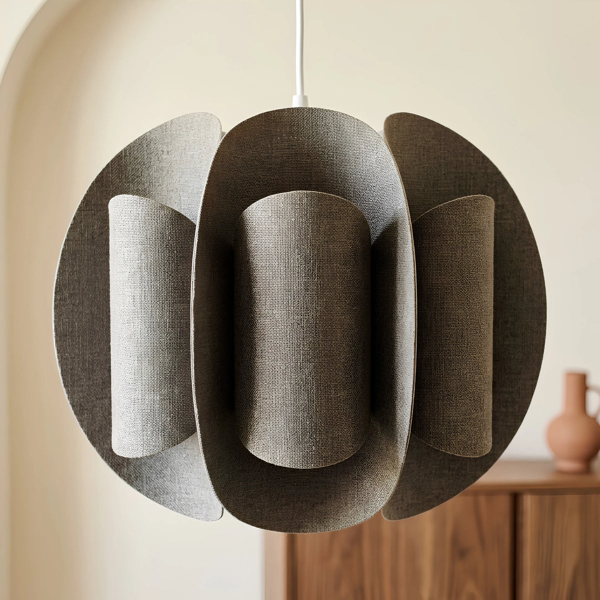 Gros plan sur une suspension en tissu taupe texturé, aux panneaux arrondis et au câble blanc.