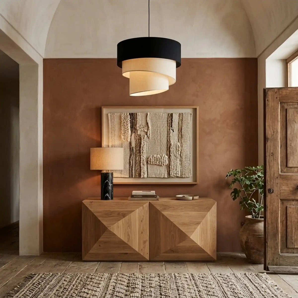 Suspension noir et écru dans une entrée au mur terracotta, console en bois géométrique