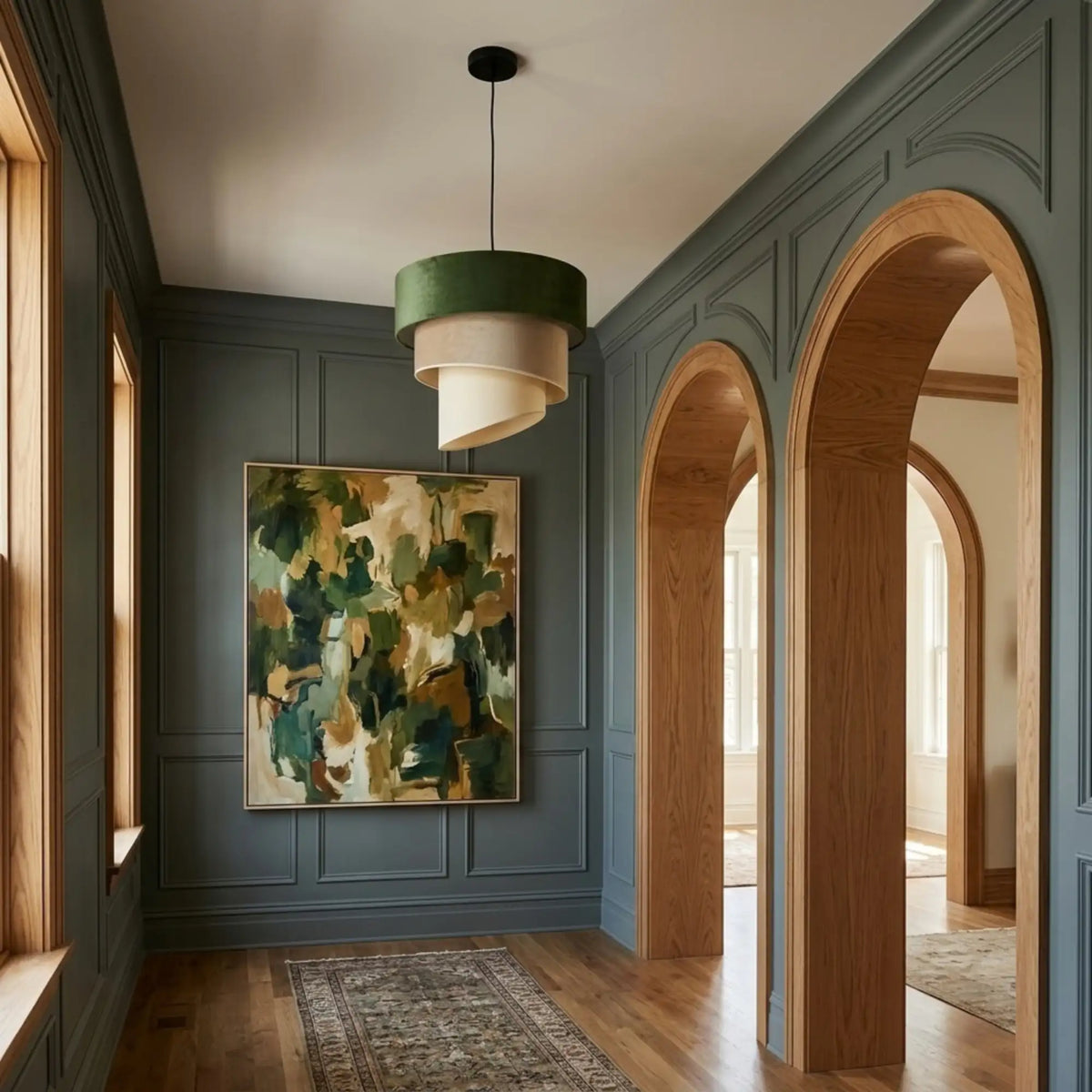 Lustre velours vert dans un couloir aux murs vert-gris moulurés et arches en chêne