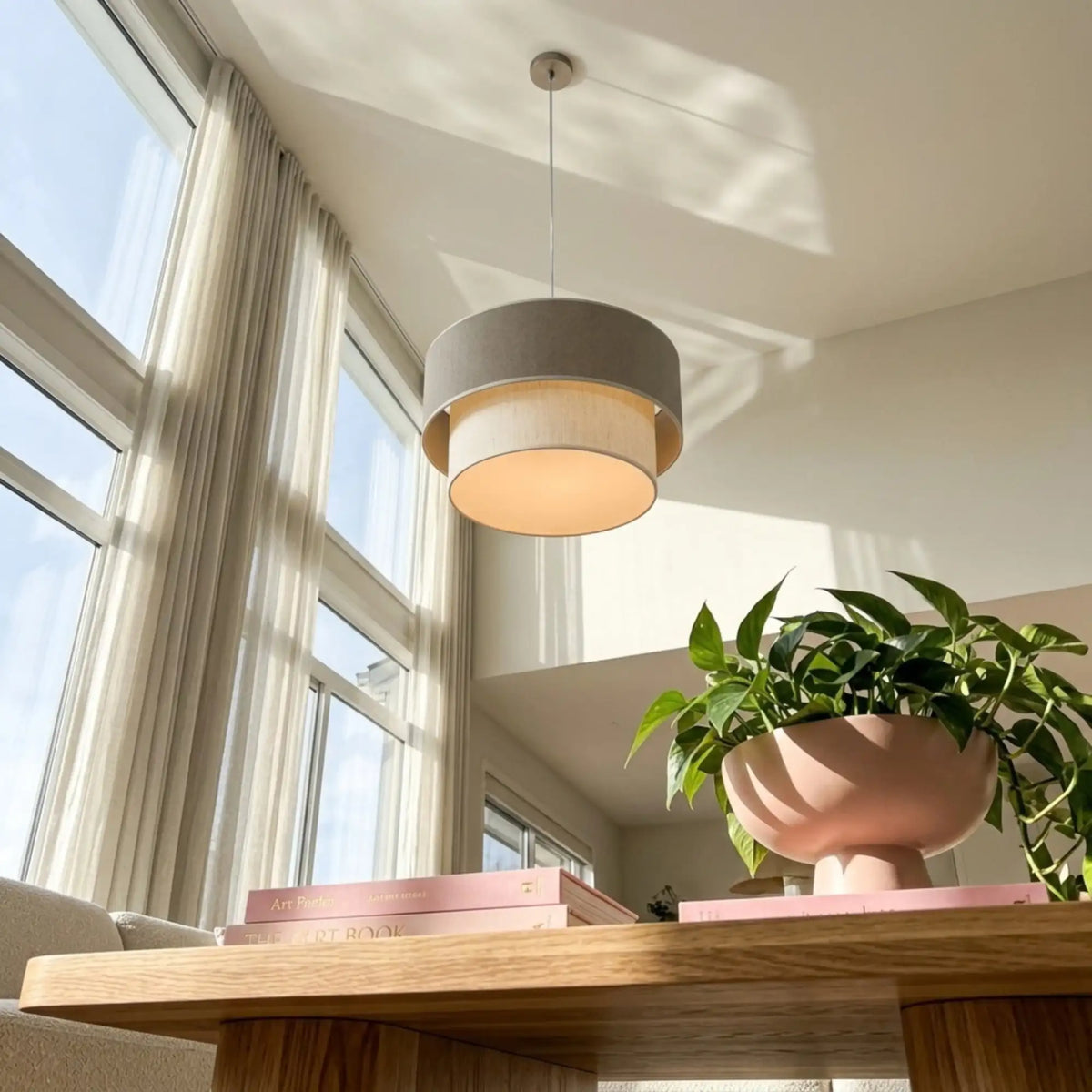 Suspension double tambour vue en contre-plongée dans un salon aux grandes baies vitrées, plante en pot rose