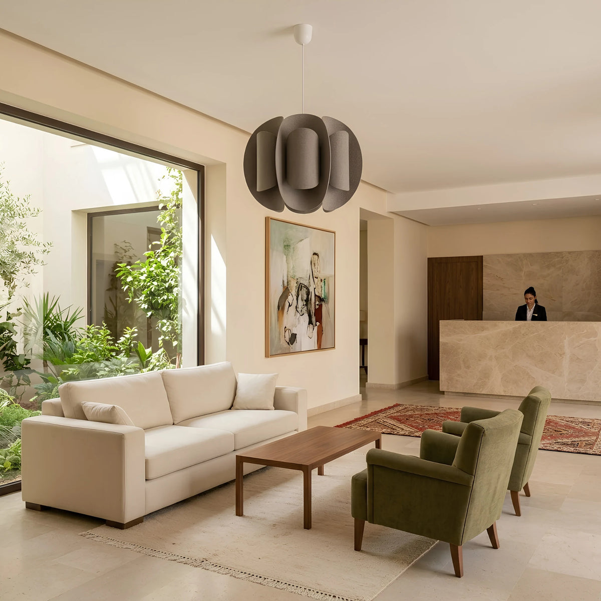 Suspension en tissu taupe dans un hall d’hôtel lumineux, au-dessus d’un canapé crème et de fauteuils verts.