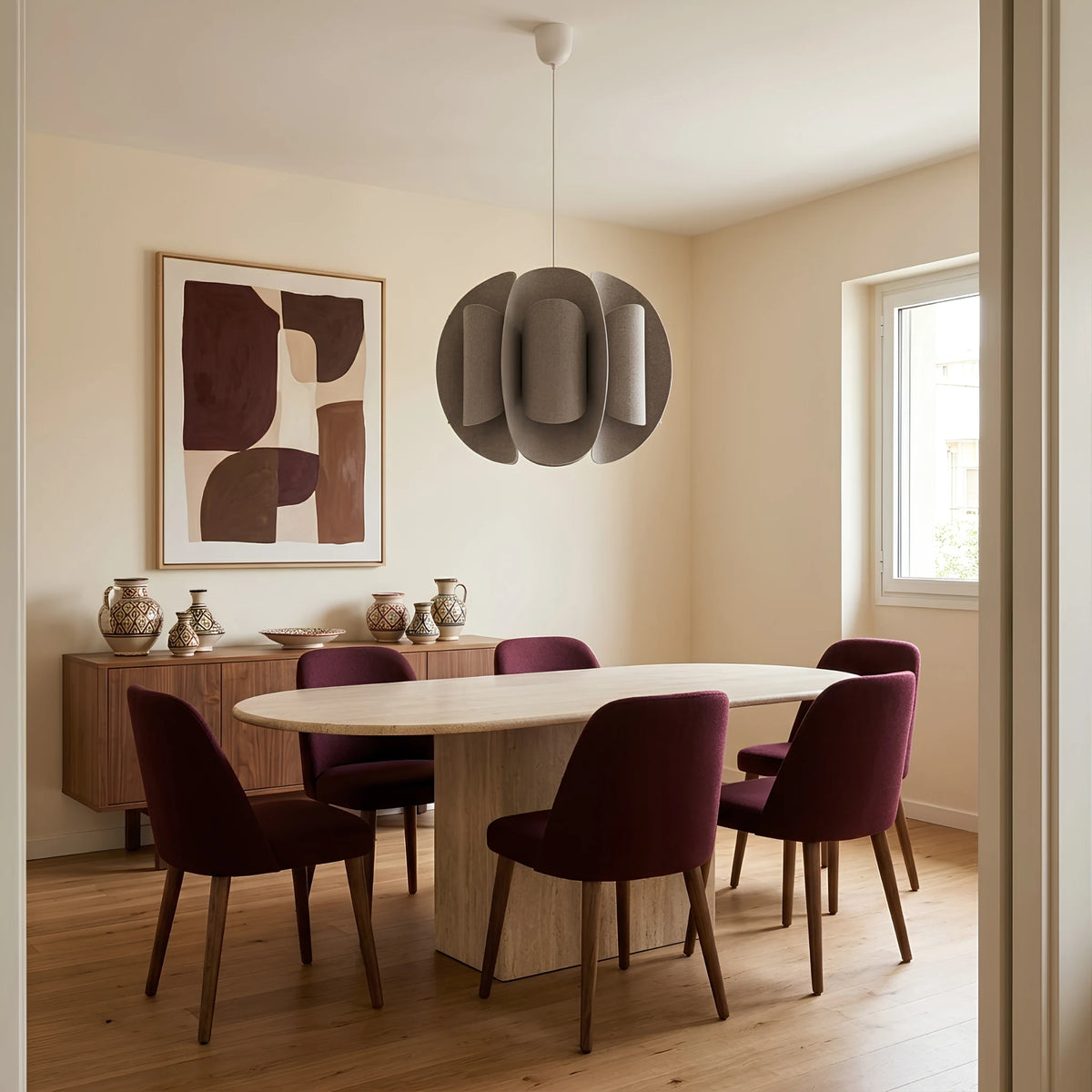Suspension en tissu taupe au-dessus d’une table ovale entourée de chaises bordeaux dans une salle à manger.